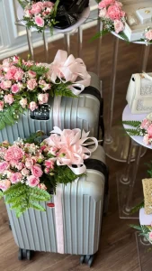Disposition of flowers around a luggage composed of pink queen Elisabeth roses, fougeres and white baby's breath and pink decoration ruban - Copie