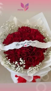 Red roses, white baby's breath bouquet and white ruban with embroidery. Cristal packaging and red ruban in - Copie